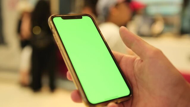 Female slides green chromakey screen on smartphone device with fingers. Human enjoy online chat, internet purchase, browse web, download new cool freeware application. 