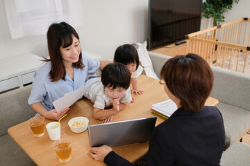 家で子供と一緒に保険外交員から保険について説明を聞く主婦と子供たち