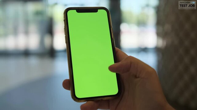 Close-up of female hand holding green chromakey smartphone in the city street. Modern wireless tech user concept.