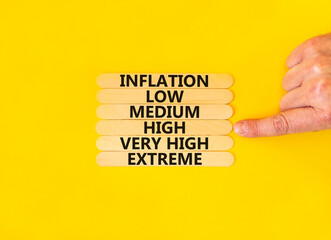 High inflation symbol. Concept word Inflation low medium high very high extreme on wooden sticks. Businessman hand. Beautiful yellow background. Business time to high inflation concept. Copy space