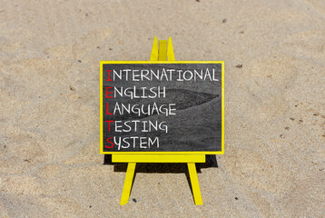 IELTS symbol. Concept words IELTS international english language testing system on black blackboard. Beautiful sand background. Business IELTS international english language testing system concept.