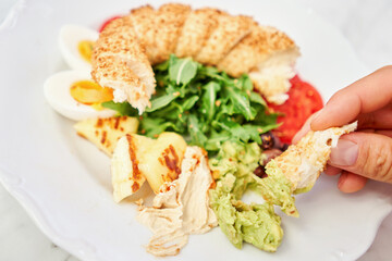A man dips a piece of bread into hummus. Turkish breakfast with simit, cheese, tomato, cucumber, olives. Breakfast with coffee in the restaurant. Morning nutritious meal