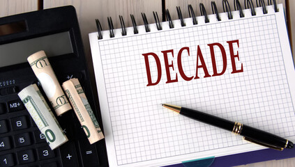 DECADE - word in a notebook on the background of a calculator and banknotes