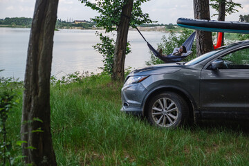 woman laying in hammock supboard on roof of car