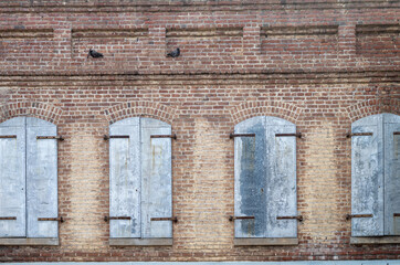 Gray Shutters on a Weathered Red Brick Wall.