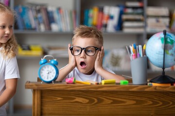 School boy dreaming with alarm clock in classroom