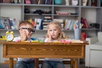 School boy dreaming with alarm clock in classroom