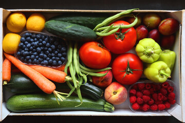 Wooden crate full of healthy seasonal fruit and vegetable. Top view, dark background.
