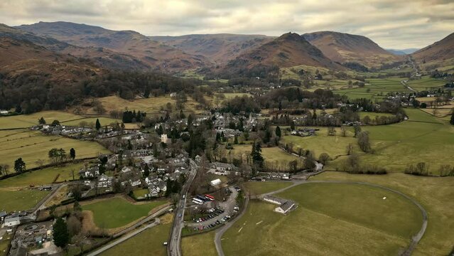 Rural Cumbrian countryside through captivating drone footage, capturing the small English town of Grasmere deep in the Lakeland fells, embraced by majestic mountains.