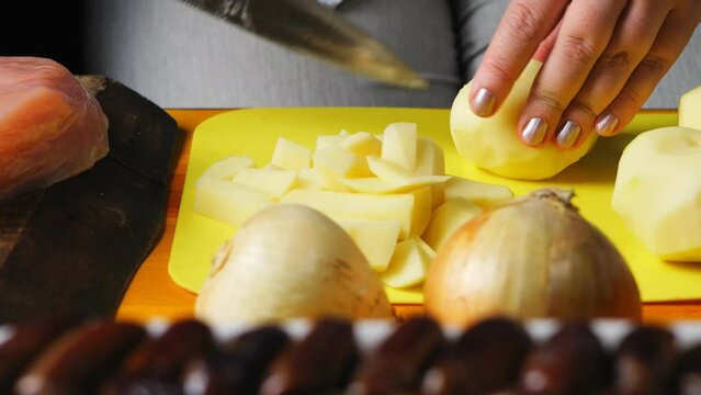 Women's hands are cutting the heartofel with a large knife on a plastic board. close-up