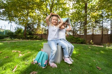 Fototapeta premium Schoolchilds hugging in park. Back to school concept.