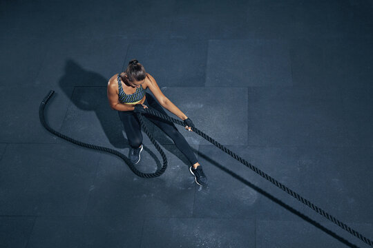 Strong caucasian woman pulling rope top view. Sporty woman in sportswear working out in gym. Strength and motivation