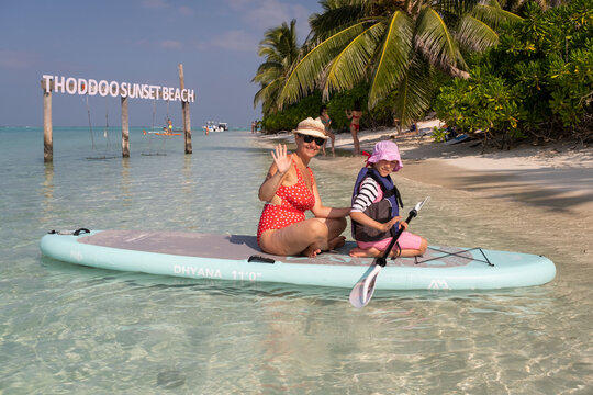 Mother with child girl puddleboarding on Maldives. Family active sport vacation concept