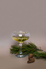 A glass of champagne surrounded by fir branches and cones on a beige background. Cocktail for the New Year. For the design of cards, invitations, posters, illustrations, presentations, flyers.