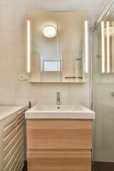 a bathroom with a sink, mirror and light on the wall above it is an image of a glass shower door