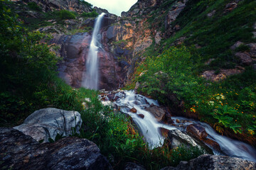 Waterfall in the mountains. The beautiful low key landscape with mountain and water stream.