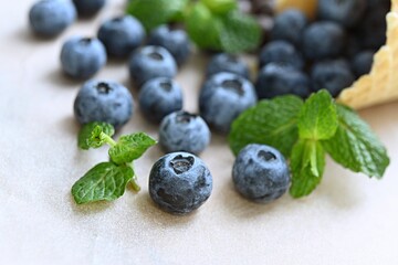 ripe blueberries spilled out of a waffle cup on a table with a green mint leaf