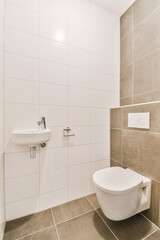 Fototapeta na wymiar a white toilet and sink in a small bathroom with tiled walls, grey flooring and beige tiles on the wall