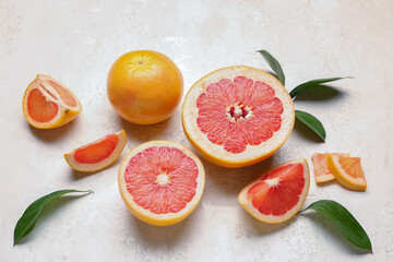 Composition with juicy grapefruit pieces and plant leaves on light background