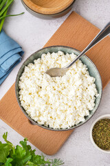 Bowl with tasty cottage cheese on light background