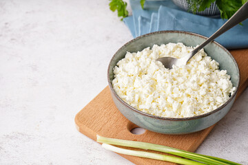 Bowl with tasty cottage cheese on light background