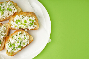 Sandwiches with tasty cottage cheese and green onion on color background