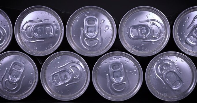 Cooled soda cans ready to drink on black background. Summer drink, thirsty, coke, juice consumption, recycle concept. Dolly shot 4k