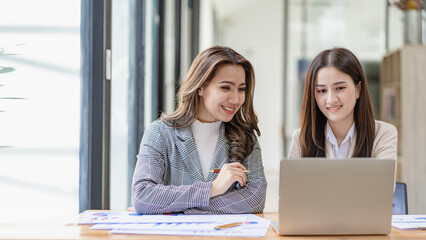Two asian businesswoman sitting and consulting business inside modern office discussing presentation of startup project idea Analyze statistics and investment markets at the office.