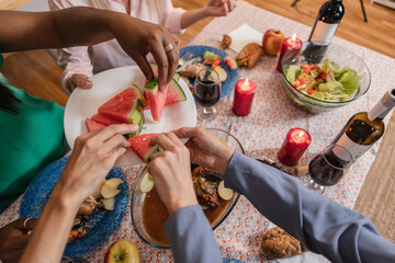 diverse hands taking piece of watermelon, dinner comes in friends who are eating fruit