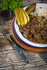 Beef stew served with barley and pickled cucumber.