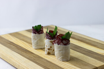 Festive snacks on a wooden board. Appetizers with sausage and cream cheese
