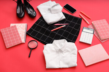 Composition with stylish school uniform, mobile phone and stationery on red background