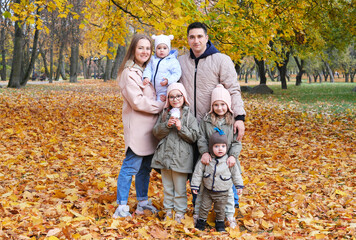 Large family posing in the autumn park. The family consists of mother, father and four children.