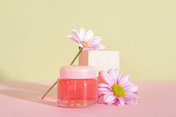 Jar of cosmetic product, plaster podium and flowers on color background