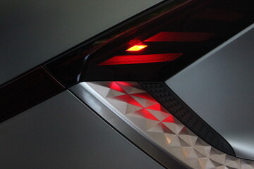 Red LED light on electric car closeup. Electric vehicle charging background image. Wallpaper of electric car. 