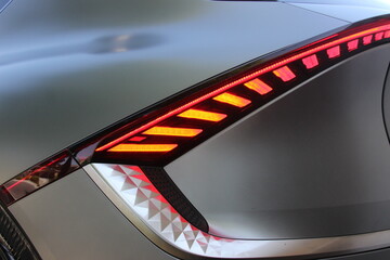 Sleek newly washed electric car rear view. Electric car wallpaper background image with LED tail lights. Closeup of charging ev. 