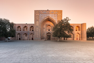 Fototapeta na wymiar Facade of ancient madrasah decorated with traditional pattern in sunrise light, Bukhara, Uzbekistan