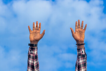 An inspirational image capturing the devotion of a Christian pastor, hands stretched out to the blue sky, fervently imploring Jesus in prayer.