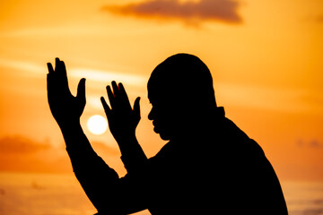 A captivating scene showcasing the silhouette of a man, arms outstretched to the sky, as he...