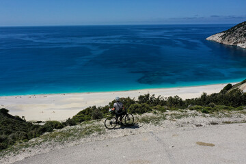 Drone photograph with cyclist on a scenic winding road above famous Myrtos Beach on the island of...
