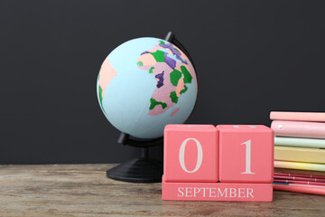 Different stationery, globe and calendar with date SEPTEMBER 1 on wooden table against black...