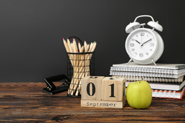 Different stationery, alarm clock and calendar with date SEPTEMBER 1 on wooden table against black chalkboard - Powered by Adobe