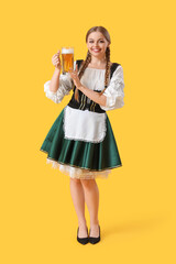 Beautiful Octoberfest waitress with beer on yellow background