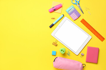 Different stationery with tablet and calculator on yellow background