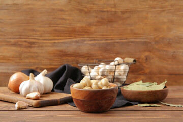 Bowl with canned mushrooms on wooden background