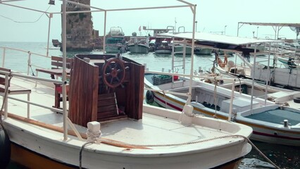 Boats rocking on waves in ancient Port of Byblos opposite ruins of port. Byblos ancient city, Jbeil, Lebanon