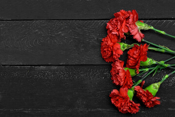 Carnation flowers on black wooden background. National Day of Prayer and Remembrance for the Victims of the Terrorist Attacks