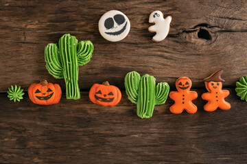Halloween homemade gingerbread cookies pumpkin Jack-o-lantern, ghosts, gingerbread man, cacti on brown wooden background.