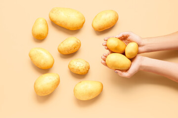 Woman holding raw potatoes on yellow background