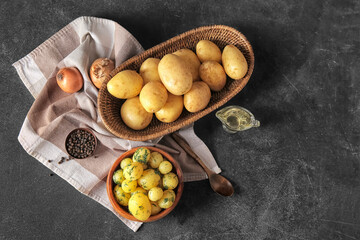 Boiled and raw baby potatoes on black background